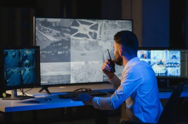 Güvenlik kamerası görüntülerini ve haritayı bilgisayarda izleyen bir adam..