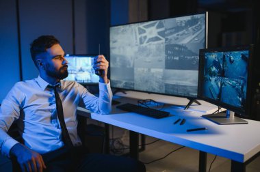 Güvenlik kamerası görüntülerini ve haritayı bilgisayarda izleyen bir adam..