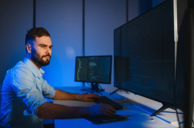 Bilgisayarda çalışan bilişim programcısı. Erkek Uzman Yaratıcı Yenilikçi Yazılım Mühendisliği Geliştirme Uygulaması, Program, Video Oyunu. Kodlama Dili Terminali. Omuz üstünden.