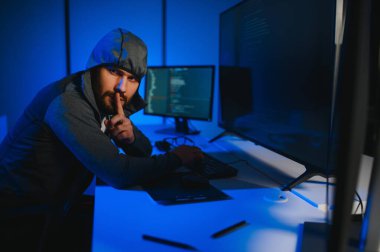 Bilgisayar programcısı karanlık odada bilgisayar kullanıyor.