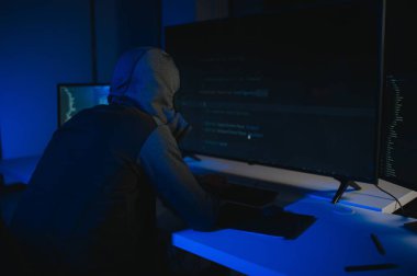Bilgisayarlı bir hacker, kapüşonlu bir masada oturan bir adam..