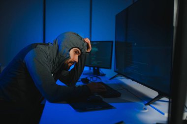 Bilgisayar programcısı karanlık odada bilgisayar kullanıyor.