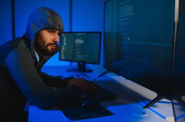 Bilgisayarlı bir hacker, kapüşonlu bir masada oturan bir adam..