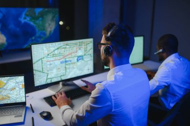 Tamirat merkezi. Seyrüsefer kontrol panosunda otururken mikrofonla çalışan erkeklerin portresi.