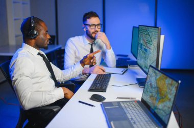 Erkek Veri Bilimadamı, Büyük Altyapı Kontrol ve İzleme Odası 'nda Kulaklık Takan Kişisel Bilgisayarda Çalışıyor. İş Çağrı Merkezi Ofisi 'nde Genç Mühendis