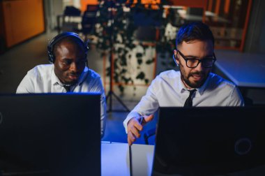 Erkek Veri Bilimadamı, Büyük Altyapı Kontrol ve İzleme Odası 'nda Kulaklık Takan Kişisel Bilgisayarda Çalışıyor. İş Çağrı Merkezi Ofisi 'nde Genç Mühendis