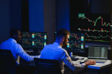 Finansal Analizci İş Gecesinde Yatırım Bankeriyle Konuşuyor. Çoklu Monitör Çalışma İstasyonunda Gerçek Zaman Stok Çizelgesi Verisi Hakkında Sohbet