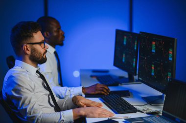 Finansal Analizci İş Gecesinde Yatırım Bankeriyle Konuşuyor. Çoklu Monitör Çalışma İstasyonunda Gerçek Zaman Stok Çizelgesi Verisi Hakkında Sohbet