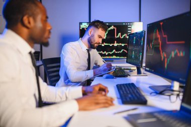 Takım çalışması kavramı. Borsacılardan oluşan bir ekip modern ofiste birçok ekran ekranı ile çalışır..