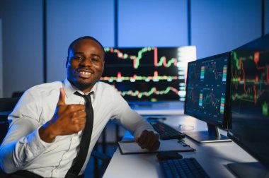 Gerçek zamanlı hisse senetleri, emtialar ve borsa grafikleri ile birlikte Multi-Monitor Workstation ile bilgisayar üzerinde çalışan finansal analist. Afrikalı Amerikalı İşadamı Gece Yatırım Bankası 'nda çalışıyor.