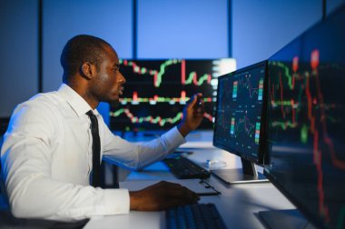 Gerçek zamanlı hisse senetleri, emtialar ve borsa grafikleri ile birlikte Multi-Monitor Workstation ile bilgisayar üzerinde çalışan finansal analist. Afrikalı Amerikalı İşadamı Gece Yatırım Bankası 'nda çalışıyor.