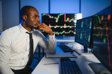 Gerçek zamanlı hisse senetleri, emtialar ve borsa grafikleri ile birlikte Multi-Monitor Workstation ile bilgisayar üzerinde çalışan finansal analist. Afrikalı Amerikalı İşadamı Gece Yatırım Bankası 'nda çalışıyor.