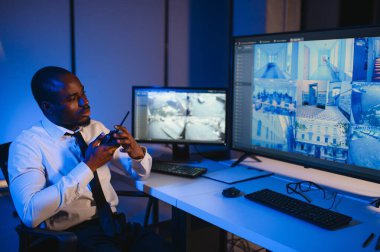 Afro-Amerikalı güvenlik görevlisi kontrol odasında telsizle konuşuyor..