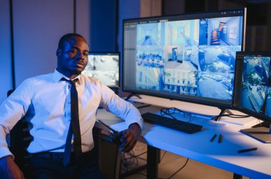 Afro-Amerikalı güvenlik görevlisi kontrol odasında telsizle konuşuyor..