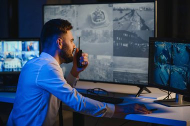 Güvenlik kamerası görüntülerini ve haritayı bilgisayarda izleyen bir adam..