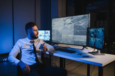 CCTV görüntülerine bakarken telsiz kullanan güvenlik sistemi operatörünün yan görüntüsü.