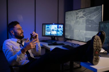 Güvenlik kamerası görüntülerini ve haritayı bilgisayarda izleyen bir adam..