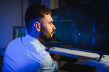 Bilgisayarda çalışan bilişim programcısı. Erkek Uzman Yaratıcı Yenilikçi Yazılım Mühendisliği Geliştirme Uygulaması, Program, Video Oyunu. Kodlama Dili Terminali. Omuz üstünden.