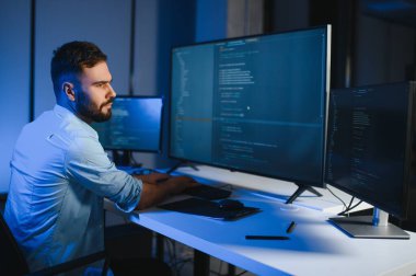 Bilgisayarda çalışan bilişim programcısı. Erkek Uzman Yaratıcı Yenilikçi Yazılım Mühendisliği Geliştirme Uygulaması, Program, Video Oyunu. Kodlama Dili Terminali. Omuz üstünden.