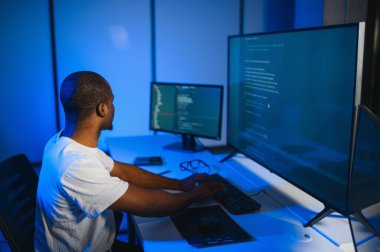 Bilgisayarda çalışan bilişim programcısı. Erkek Uzman Yaratıcı Yenilikçi Yazılım Mühendisliği Geliştirme Uygulaması, Program, Video Oyunu. Kodlama Dili Terminali. Omuz üstünden.