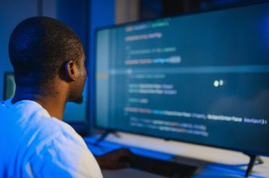 Bilgisayarda çalışan bilişim programcısı. Erkek Uzman Yaratıcı Yenilikçi Yazılım Mühendisliği Geliştirme Uygulaması, Program, Video Oyunu. Kodlama Dili Terminali. Omuz üstünden.