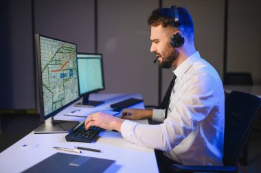 Tamirat merkezi. Seyrüsefer kontrol panosunda otururken mikrofonla çalışan bir adamın portresi.