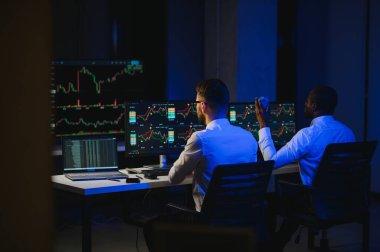 Finansal Analizci İş Gecesinde Yatırım Bankeriyle Konuşuyor. Çoklu Monitör Çalışma İstasyonunda Gerçek Zaman Stok Çizelgesi Verisi Hakkında Sohbet