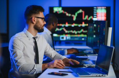 Finansal Analizci İş Gecesinde Yatırım Bankeriyle Konuşuyor. Çoklu Monitör Çalışma İstasyonunda Gerçek Zaman Stok Çizelgesi Verisi Hakkında Sohbet