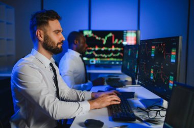 Finansal Analizci İş Gecesinde Yatırım Bankeriyle Konuşuyor. Çoklu Monitör Çalışma İstasyonunda Gerçek Zaman Stok Çizelgesi Verisi Hakkında Sohbet