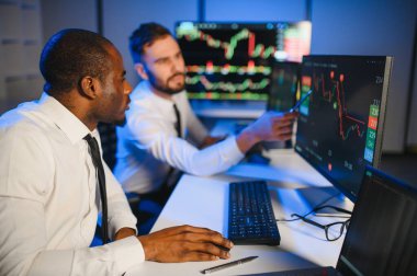 Finansal Analizci İş Gecesinde Yatırım Bankeriyle Konuşuyor. Çoklu Monitör Çalışma İstasyonunda Gerçek Zaman Stok Çizelgesi Verisi Hakkında Sohbet