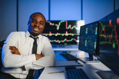 Gerçek zamanlı hisse senetleri, emtialar ve borsa grafikleri ile birlikte Multi-Monitor Workstation ile bilgisayar üzerinde çalışan finansal analist. Afrikalı Amerikalı İşadamı Gece Yatırım Bankası 'nda çalışıyor.