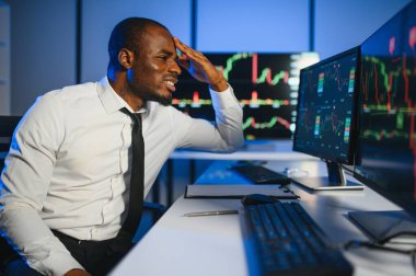 Gerçek zamanlı hisse senetleri, emtialar ve borsa grafikleri ile birlikte Multi-Monitor Workstation ile bilgisayar üzerinde çalışan finansal analist. Afrikalı Amerikalı İşadamı Gece Yatırım Bankası 'nda çalışıyor.