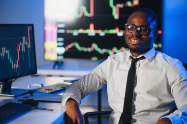 Gerçek zamanlı hisse senetleri, emtialar ve borsa grafikleri ile birlikte Multi-Monitor Workstation ile bilgisayar üzerinde çalışan finansal analist. Afrikalı Amerikalı İşadamı Gece Yatırım Bankası 'nda çalışıyor.