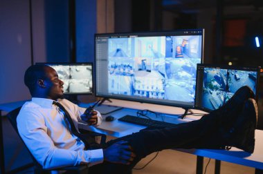 Afro-Amerikan güvenlik görevlisi ya da merkez bilgisayar ve telsiz kullanıyor, ekranlara bakıyor..