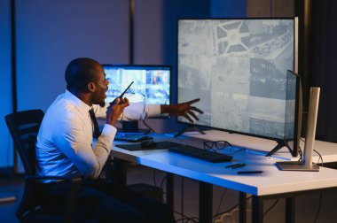 Afro-Amerikalı güvenlik görevlisi kontrol odasında telsizle konuşuyor..