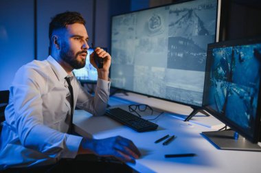 Güvenlik kamerası görüntülerini ve haritayı bilgisayarda izleyen bir adam..