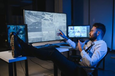 CCTV görüntülerine bakarken telsiz kullanan güvenlik sistemi operatörünün yan görüntüsü.