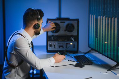 Gizli ajan kayıt cihazını dinliyormuş. Memur kulaklıkla dinleme yapıyor..