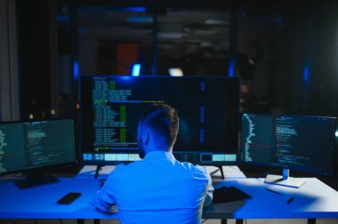 Bilgisayarda çalışan bilişim programcısı. Erkek Uzman Yaratıcı Yenilikçi Yazılım Mühendisliği Geliştirme Uygulaması, Program, Video Oyunu. Kodlama Dili Terminali. Omuz üstünden.