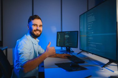 Bilgisayarda çalışan bilişim programcısı. Erkek Uzman Yaratıcı Yenilikçi Yazılım Mühendisliği Geliştirme Uygulaması, Program, Video Oyunu. Kodlama Dili Terminali. Omuz üstünden.