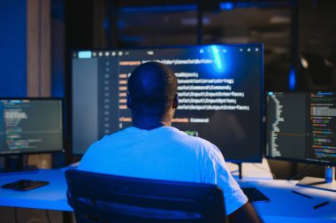 Bilgisayarda çalışan bilişim programcısı. Erkek Uzman Yaratıcı Yenilikçi Yazılım Mühendisliği Geliştirme Uygulaması, Program, Video Oyunu. Kodlama Dili Terminali. Omuz üstünden.