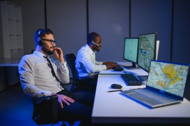 Tamirat merkezi. Seyrüsefer kontrol panosunda otururken mikrofonla çalışan erkeklerin portresi.