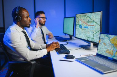 Erkek Veri Bilimadamı, Büyük Altyapı Kontrol ve İzleme Odası 'nda Kulaklık Takan Kişisel Bilgisayarda Çalışıyor. İş Çağrı Merkezi Ofisi 'nde Genç Mühendis