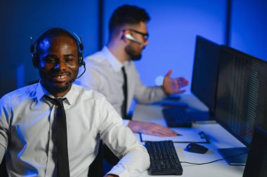 Erkek Veri Bilimadamı, Büyük Altyapı Kontrol ve İzleme Odası 'nda Kulaklık Takan Kişisel Bilgisayarda Çalışıyor. İş Çağrı Merkezi Ofisi 'nde Genç Mühendis