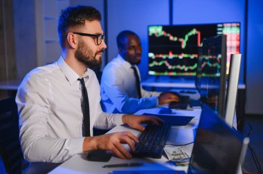 Finansal Analizci İş Gecesinde Yatırım Bankeriyle Konuşuyor. Çoklu Monitör Çalışma İstasyonunda Gerçek Zaman Stok Çizelgesi Verisi Hakkında Sohbet