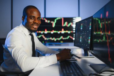 Gerçek zamanlı hisse senetleri, emtialar ve borsa grafikleri ile birlikte Multi-Monitor Workstation ile bilgisayar üzerinde çalışan finansal analist. Afrikalı Amerikalı İşadamı Gece Yatırım Bankası 'nda çalışıyor.