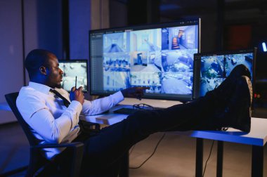 Afro-Amerikan güvenlik görevlisi ya da merkez bilgisayar ve telsiz kullanıyor, ekranlara bakıyor..