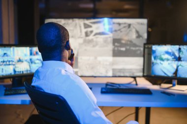 Afro-Amerikalı güvenlik görevlisi kontrol odasında telsizle konuşuyor..