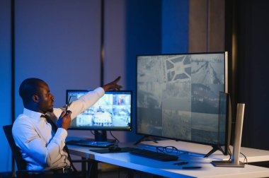 Afro-Amerikalı güvenlik görevlisi kontrol odasında telsizle konuşuyor..