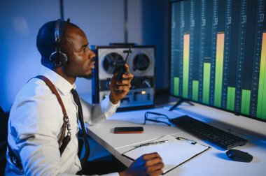 Gizli ajan kayıt cihazını dinliyormuş. Memur kulaklıkla dinleme yapıyor..